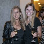 Two women pose with drinks in hand at a cocktail hour at GCOS