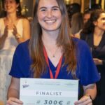 A young woman poses smiling with an award