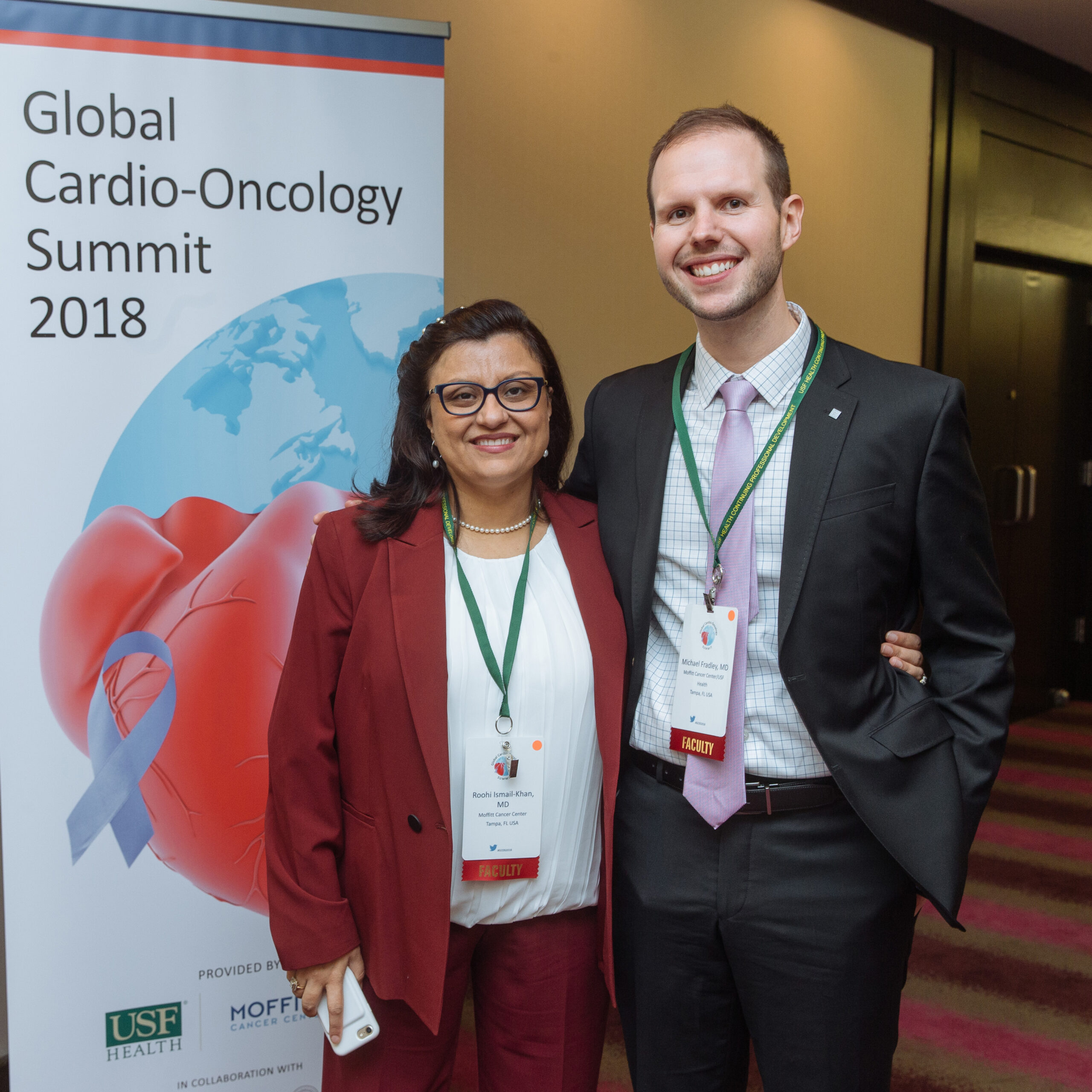 Two IC-OS Members pose, smiling for a picture in front of a banner for GCOS 2018