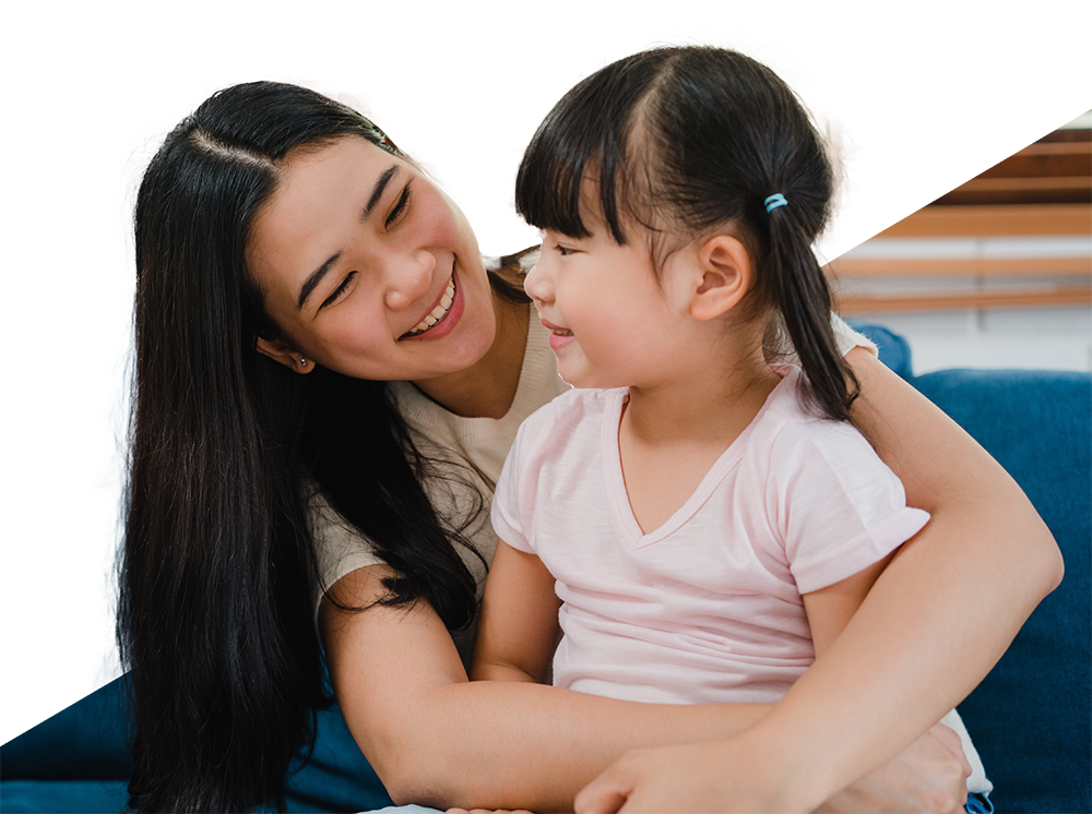 An asian woman smiles while hugging her daughter