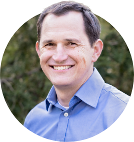 Joshua Mitchell Circle Joshua Mitchell, a white cardio-oncologist with dark hair and a blue collared shirt