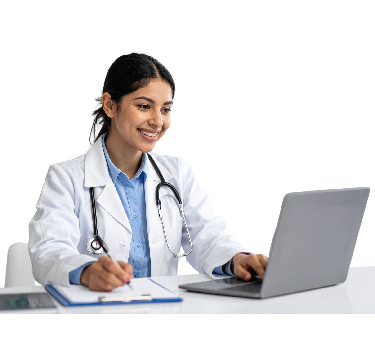 An Indian or Hispanic doctor with dark, medium length hair tucked behind her ear sits at a desk in a lab coat, blue shirt, and stethoscope. She writes on a paper on a clipboard while scrolling a grey laptop